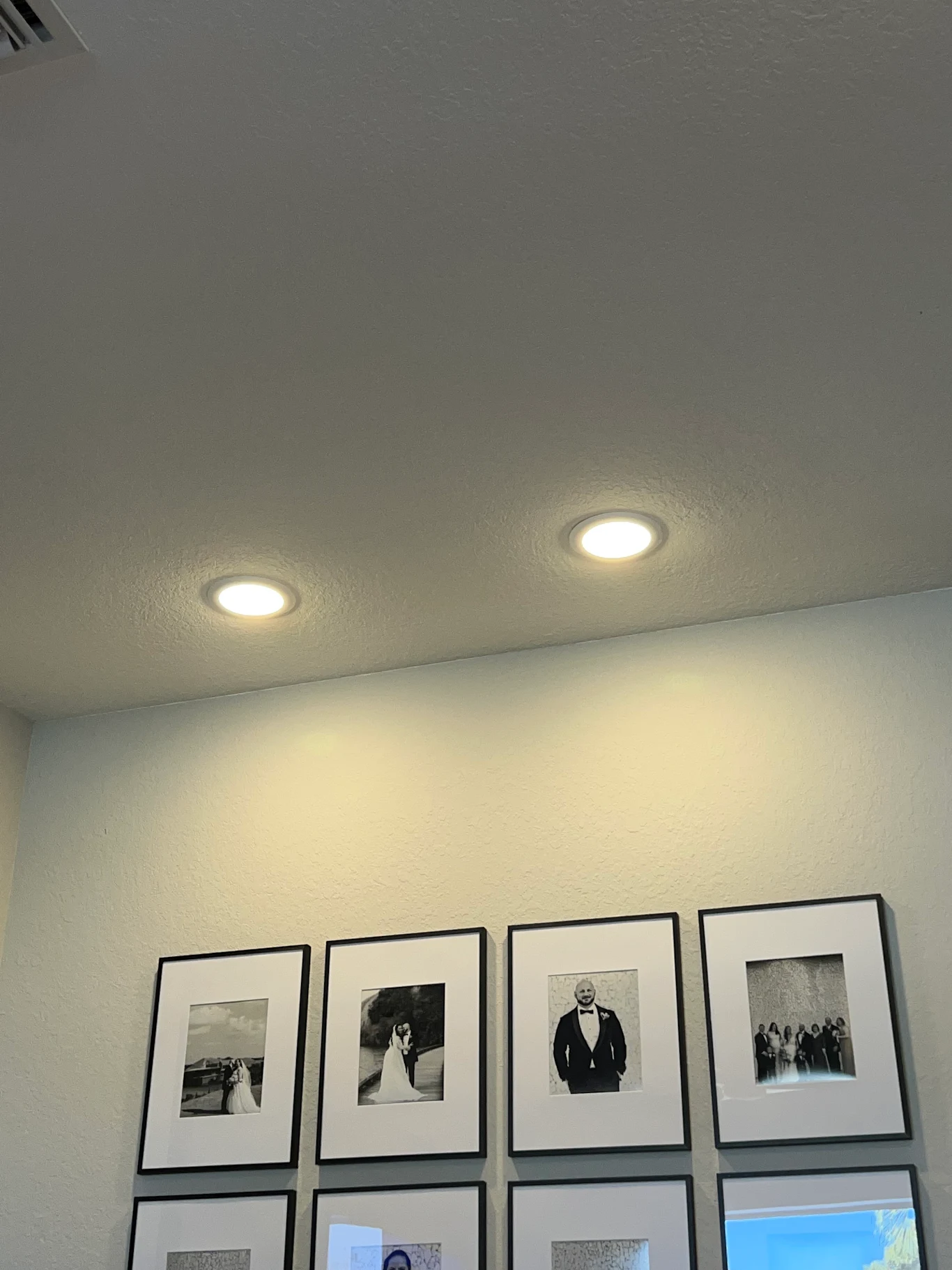 Recessed pot lights above a framed photo wall
